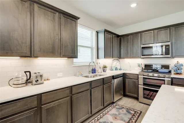 a kitchen with a refrigerator a stove a sink dishwasher with a dining table and chairs