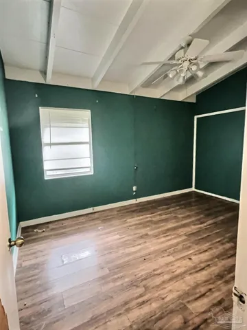 an empty room with wooden floor and fan