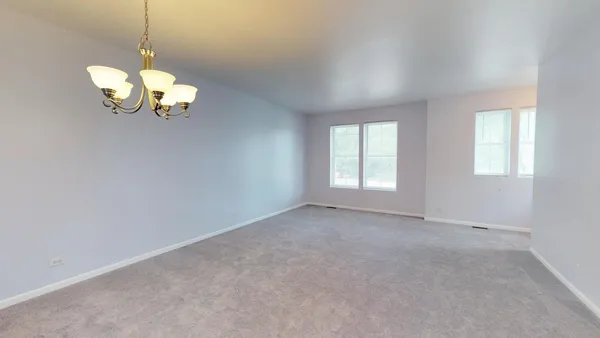a view of a room with a chandelier fan and windows