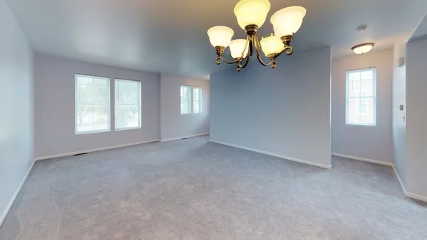 a view of a livingroom with a chandelier fan and windows