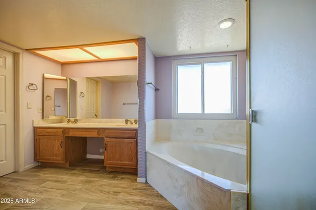 a bathroom with a sink double vanity granite tub shower and a mirror