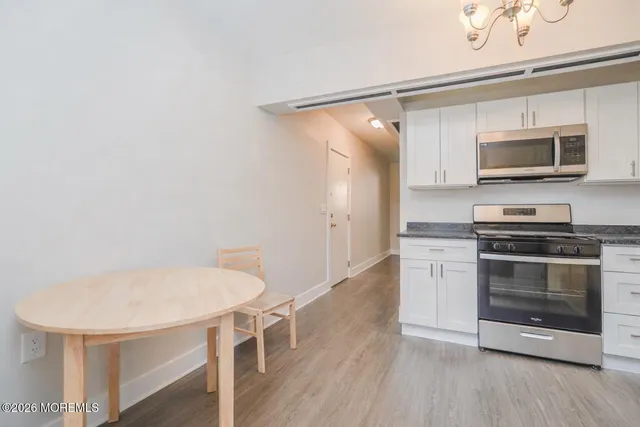 a kitchen with stainless steel appliances a stove a microwave and white cabinets