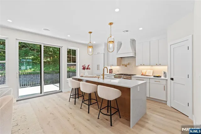a kitchen with stainless steel appliances granite countertop a stove a refrigerator a sink dishwasher with a dining table and chairs with wooden floor