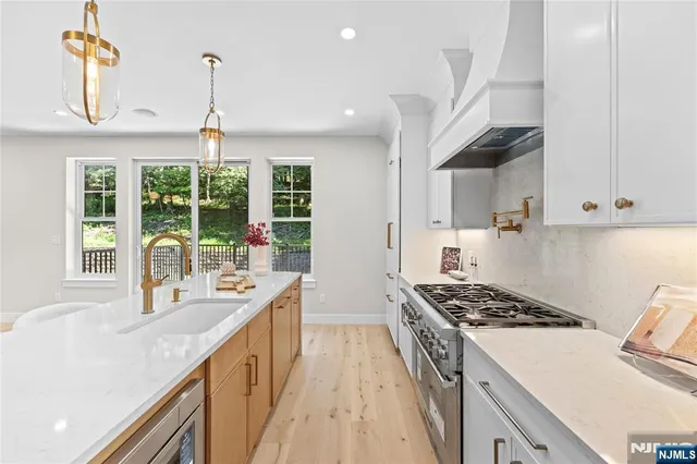 a kitchen with stainless steel appliances granite countertop a sink a stove and a wooden floors