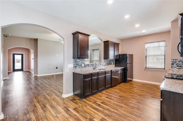 a view of a kitchen with kitchen island wooden floor center island and stainless steel appliances