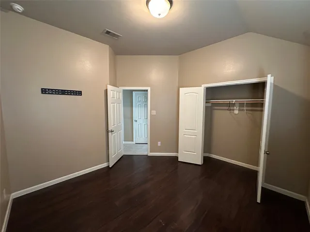 a view of an empty room with wooden floor and closet