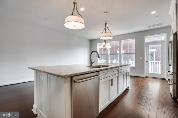 a kitchen with stainless steel appliances granite countertop a sink a stove and wooden floors