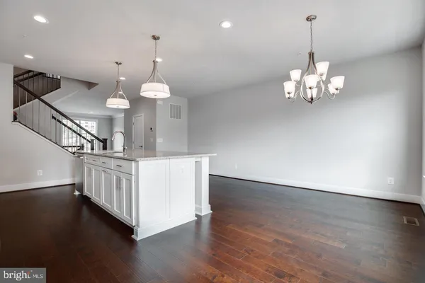 a view of a room with wooden floor a chandelier a refrigerator and windows