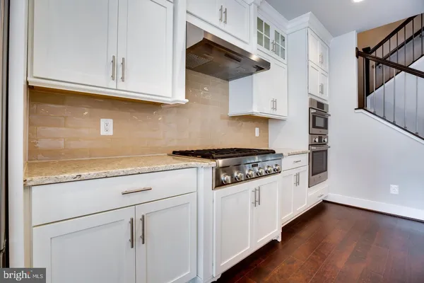 a kitchen with stainless steel appliances granite countertop a stove and a wooden floors
