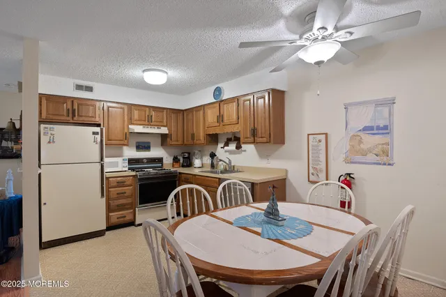 a kitchen with stainless steel appliances granite countertop a dining table chairs refrigerator and cabinets