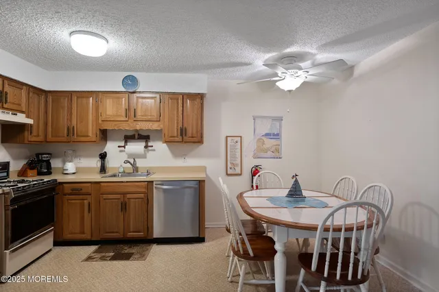 a kitchen with stainless steel appliances granite countertop a sink a stove a dining table and chairs