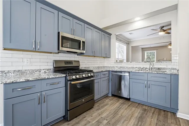 a kitchen with granite countertop a sink cabinets and stainless steel appliances