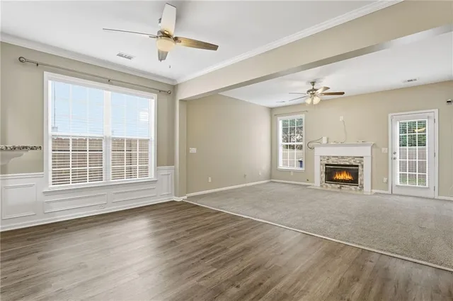 a view of an empty room with wooden floor fireplace and a window