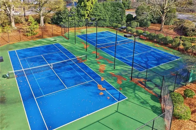 a view of a tennis ground with large trees