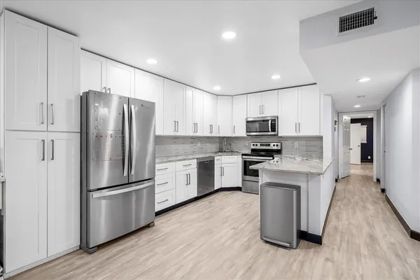 a kitchen with wooden floors stainless steel appliances and cabinets
