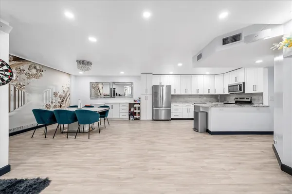 a living room with stainless steel appliances furniture and kitchen view