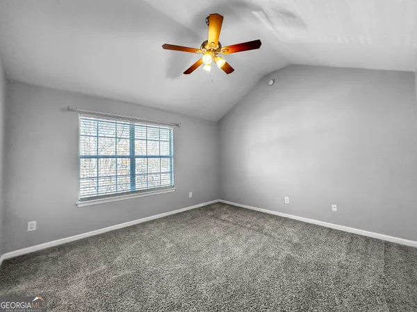 an empty room with chandelier fan and windows
