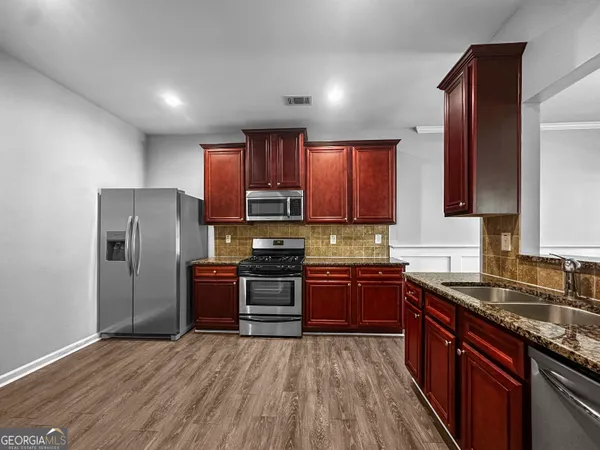a kitchen with stainless steel appliances granite countertop a refrigerator stove top oven and sink