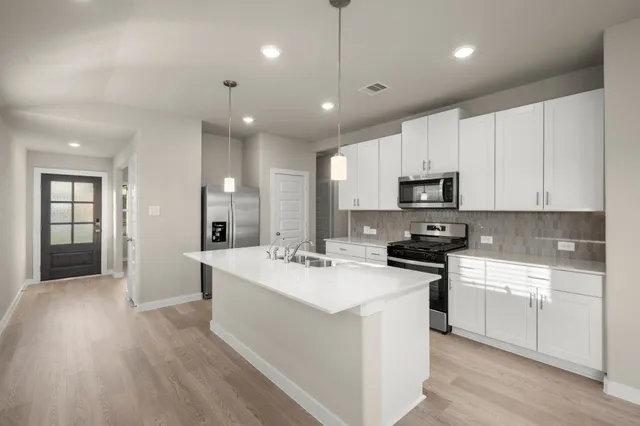 a kitchen with counter top space sink stove and refrigerator
