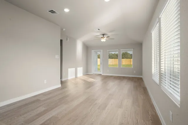 a view of an empty room with a window and wooden floor