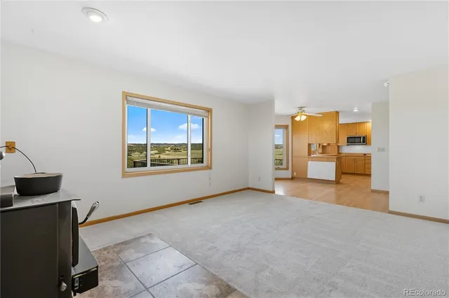 a view of an empty room with a window and a kitchen