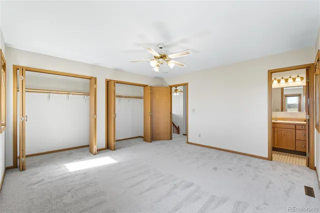 an empty room with chandelier fan and windows