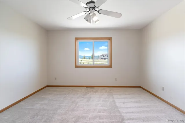 an empty room with a window and a ceiling fan