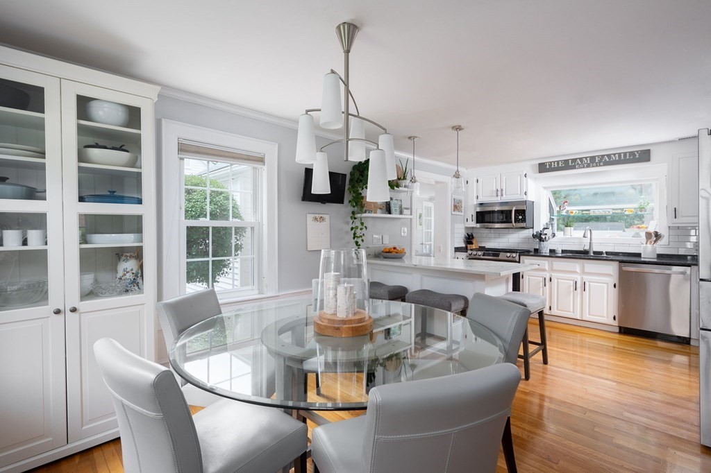 1054 Brook Road Milton, MA 02186 - Photo 3 of 23 a dining room with furniture a kitchen wooden floor and a chandelier