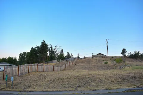 a view of a dry yard with wooden fence