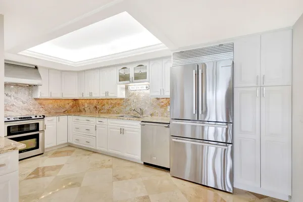 a view of a open kitchen with a refrigerator and cabinets