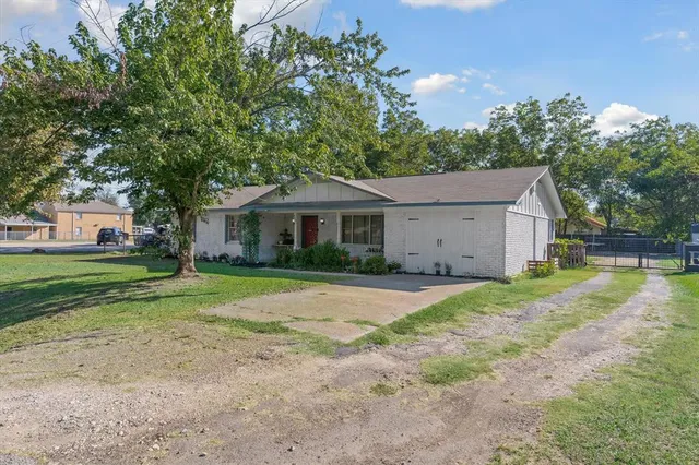 a view of a house with a yard and large tree