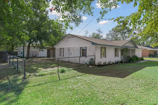 a view of a house with a yard and a large tree