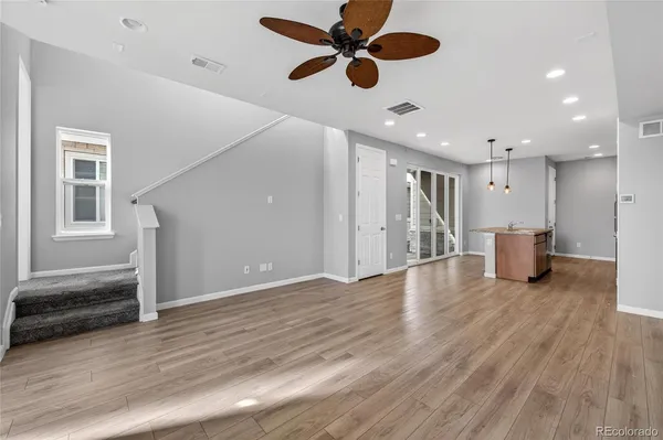 a view of an empty room with wooden floor and a ceiling fan