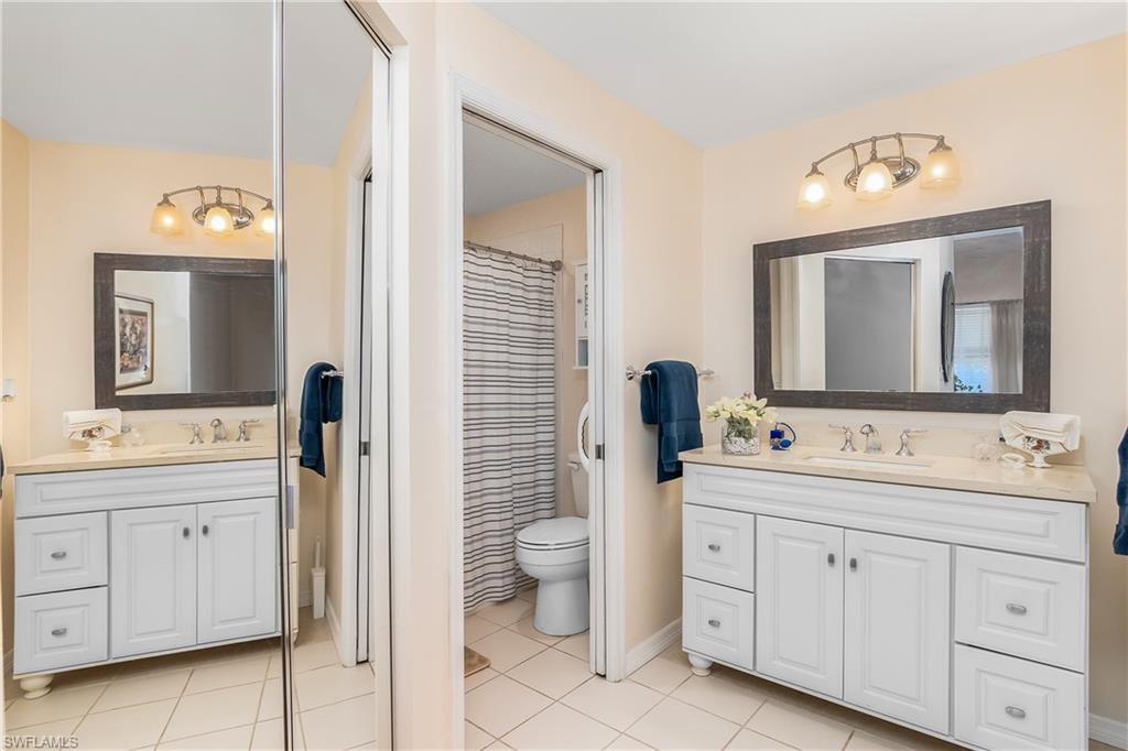 613 Windsor Square, Unit 101 Naples, FL 34104 - Photo 16 of 23 a spacious bathroom with a double vanity sink a mirror and a toilet