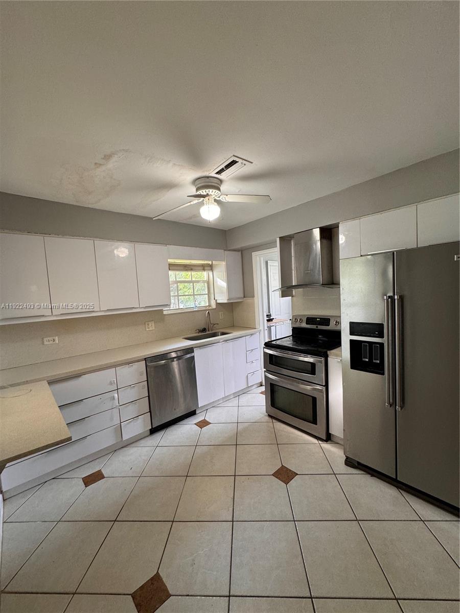 316 Southwest 2nd Terrace Hallandale Beach, FL 33009 - Photo 5 of 16 a kitchen with stainless steel appliances granite countertop a refrigerator a stove a sink dishwasher and white cabinets with wooden floor