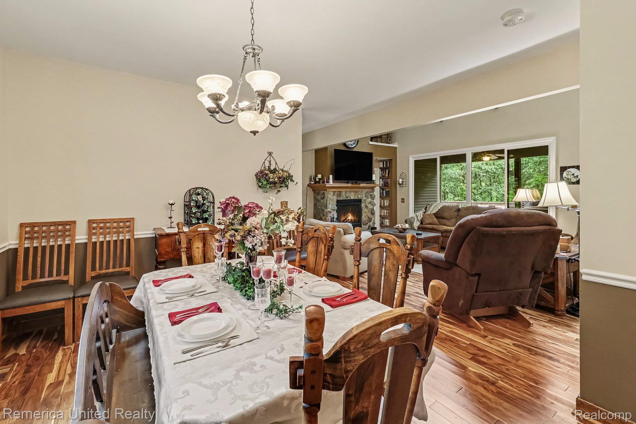 20962 Wasson Road Gregory, MI 48137 - Photo 7 of 39 Open-concept dining and living areas featuring wood-finish flooring, a stone fireplace, and sliding glass doors