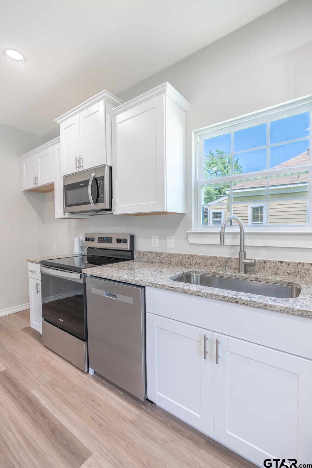 233 Harrison Street Longview, TX 75601 - Photo 16 of 44 a kitchen with granite countertop a sink cabinets and stainless steel appliances
