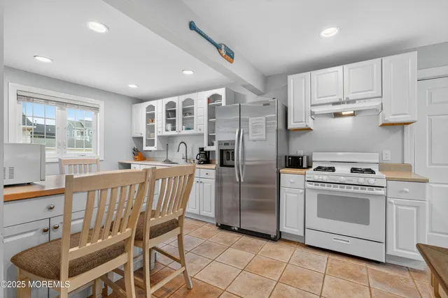 a kitchen with stainless steel appliances a stove a sink dishwasher a refrigerator and cabinets with wooden floor
