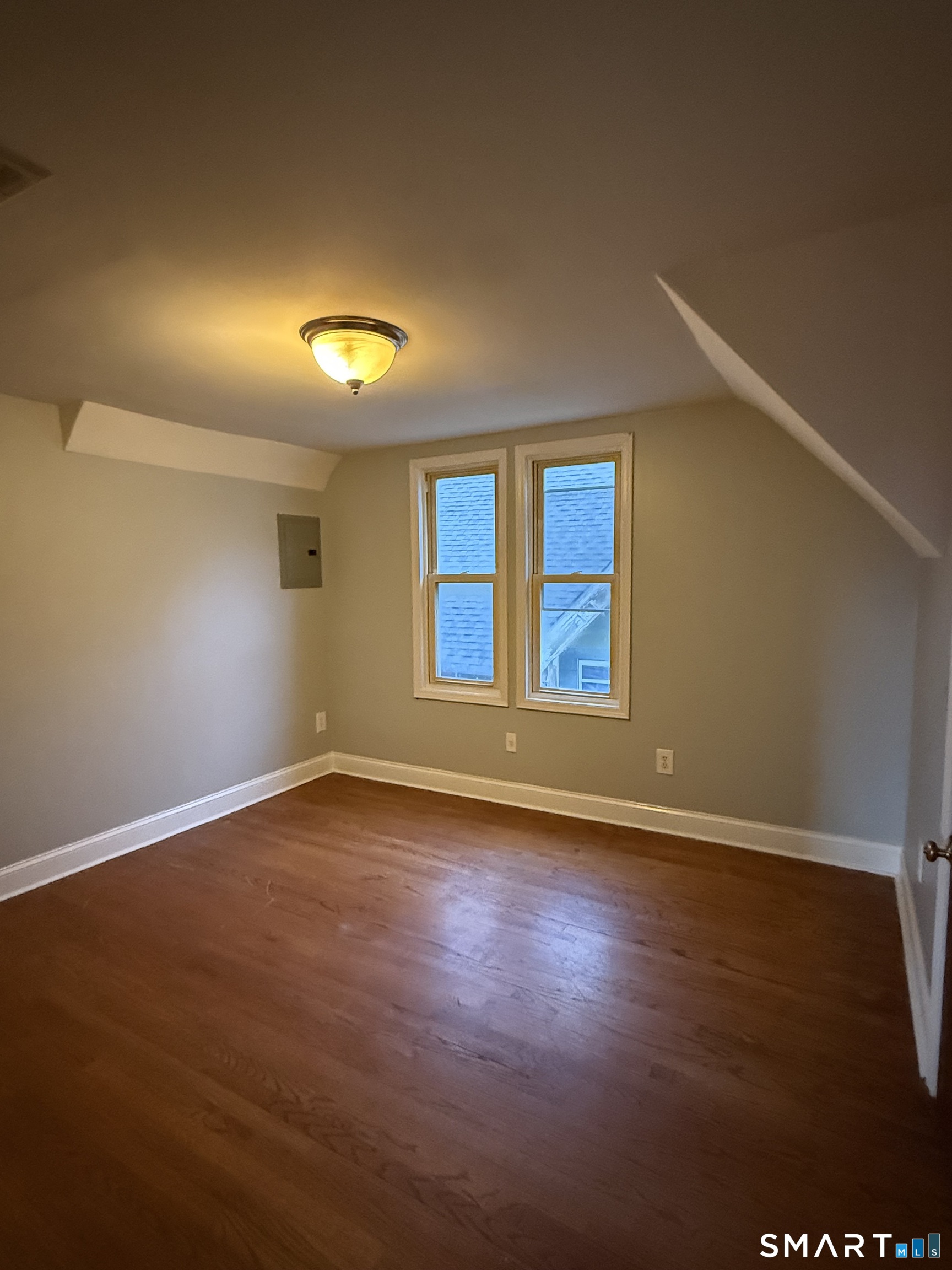 an empty room with wooden floor and windows