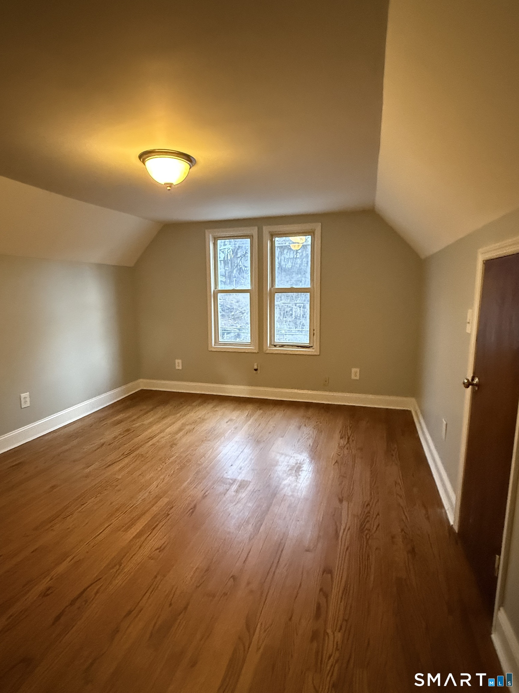 21 North Walnut Street, Unit 3 Waterbury, CT 06704 - Photo 2 of 8 an empty room with wooden floor and windows