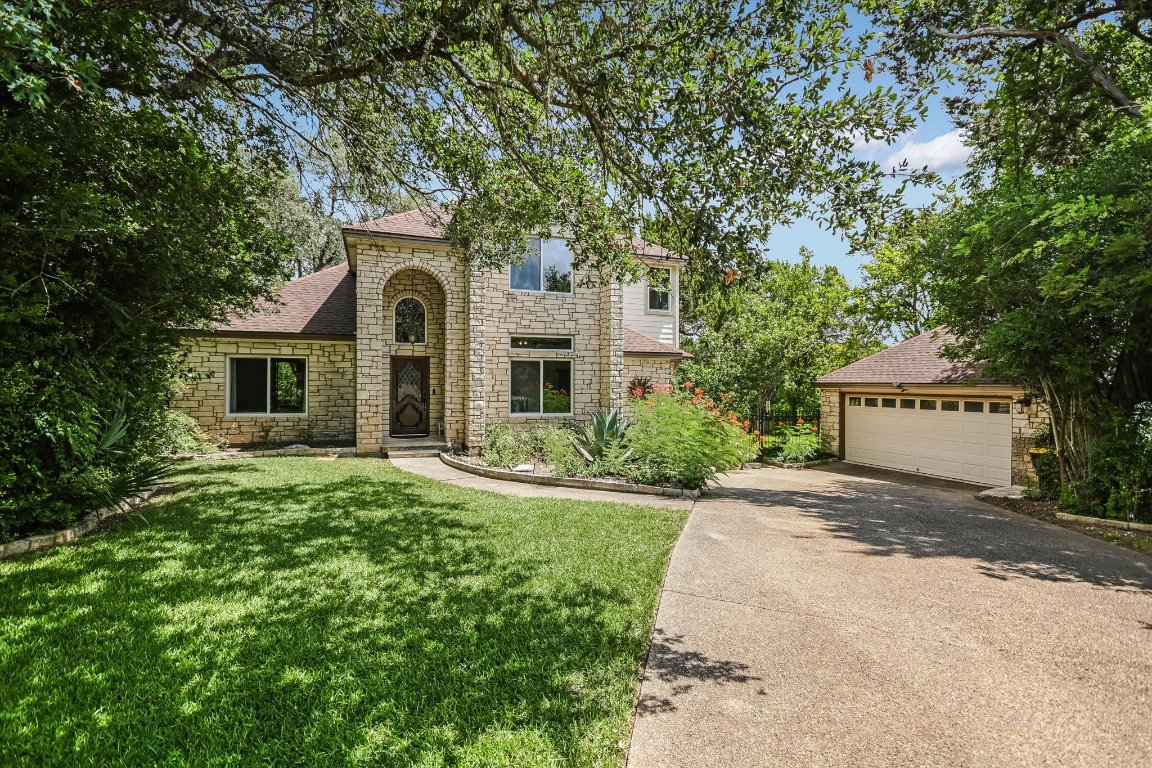 6806 Rio Bravo Lane Austin, TX 78737 - Photo 1 of 1 Traditional-style house with stone siding, a detached garage, a front yard, and entrance gate to back yard