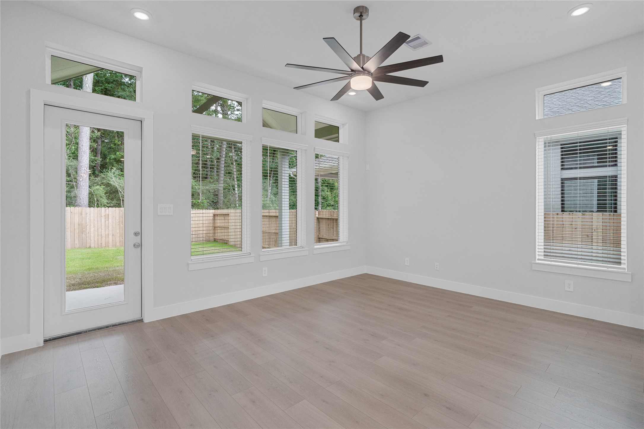 2035 Frst Strm Way Conroe, TX 77304 - Photo 26 of 45 A bright and airy open-concept family room featuring laminate flooring, high ceilings with recessed lighting and ceiling fan, abundant natural light from large windows, and an access door to the back covered patio.