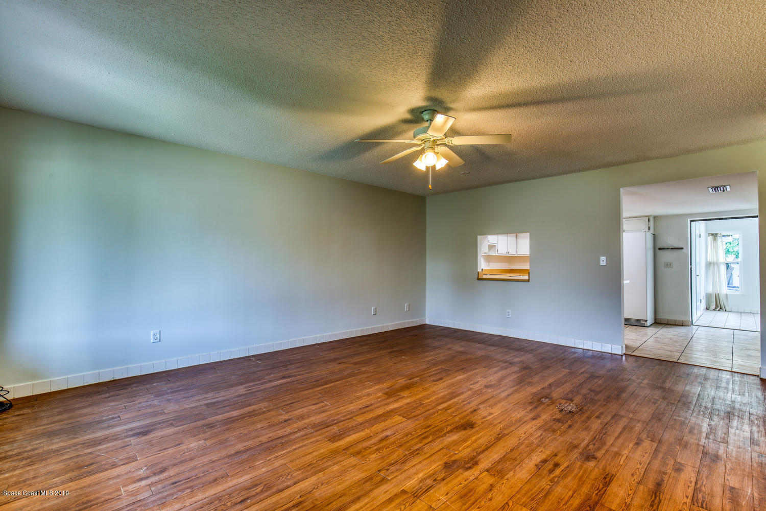 201 Ocean View Lane Melbourne, FL 32903 - Photo 4 of 21 an empty room with wooden floor chandelier fan and windows