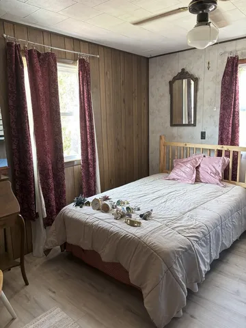 a bedroom with a bed painting on wall and a window