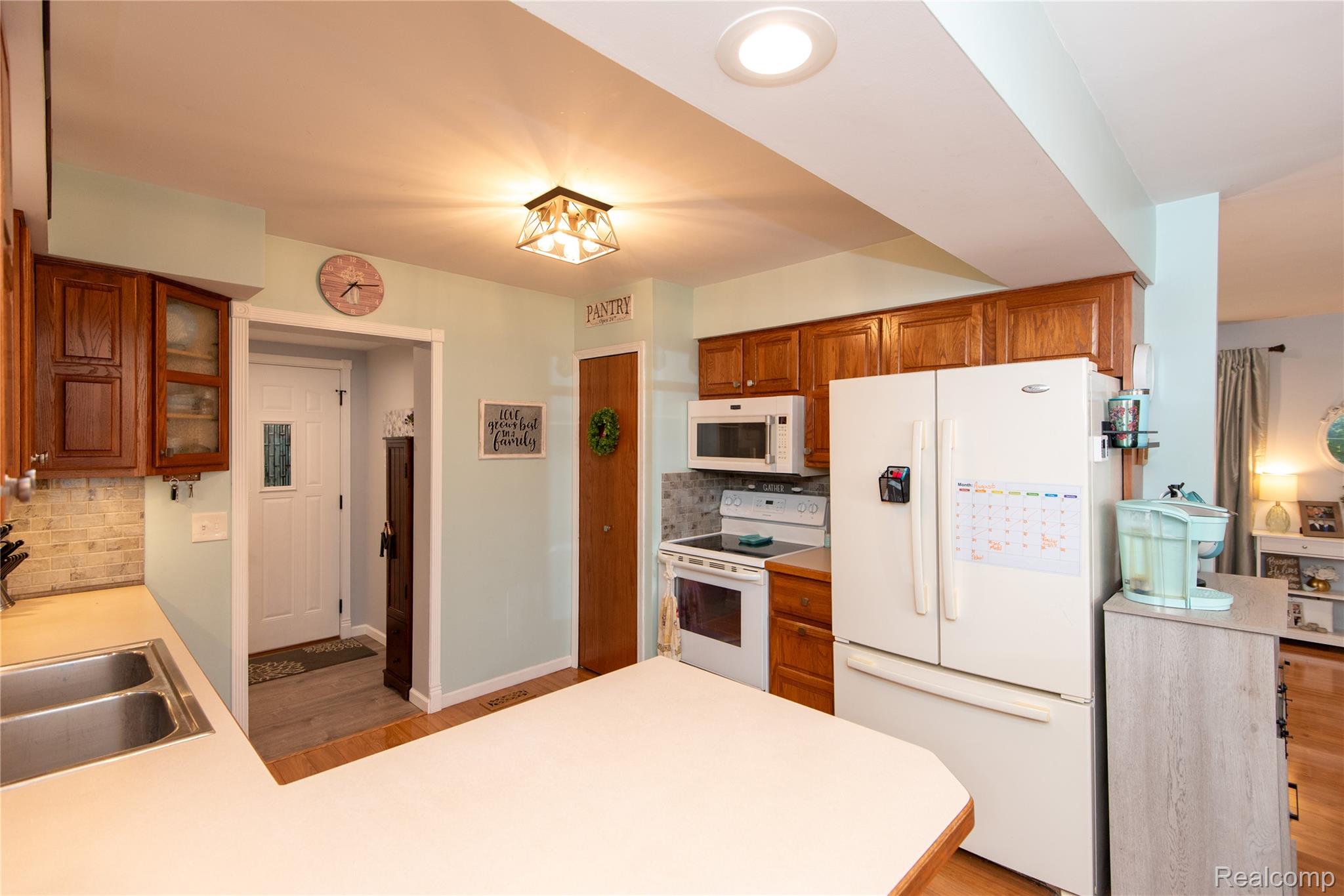 4395 Regency Road Swartz Creek, MI 48473 - Photo 25 of 67 Wood-finish cabinetry, stainless steel double basin sink, white built-in microwave, and wood-finish flooring