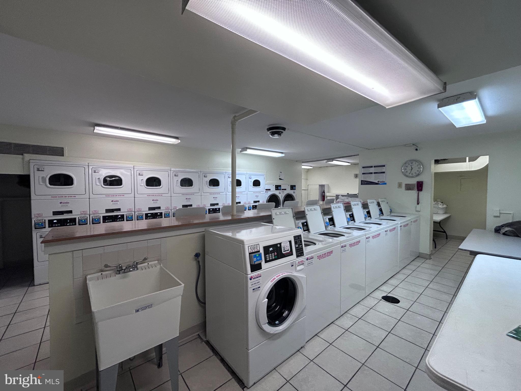 1111 University Boulevard West, Unit 1411A Silver Spring, MD 20902 - Photo 32 of 36 a large white kitchen with a stove a sink dishwasher and a refrigerator with wooden floor