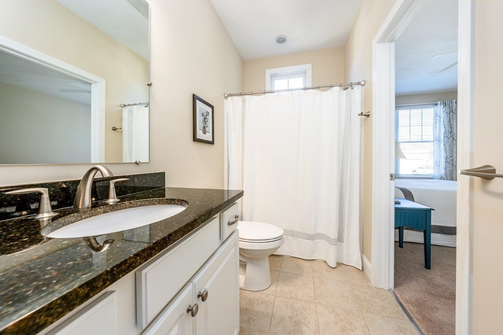 24 Grey Hawk Drive, Unit 646 Mashpee, MA 02649 - Photo 17 of 24 a bathroom with a granite countertop sink a toilet a mirror and shower