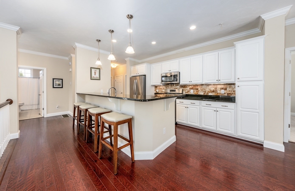 24 Grey Hawk Drive, Unit 646 Mashpee, MA 02649 - Photo 4 of 24 a kitchen with stainless steel appliances granite countertop wooden floors and white cabinets