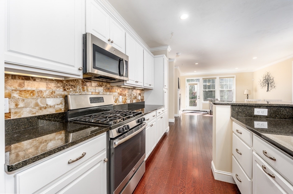 24 Grey Hawk Drive, Unit 646 Mashpee, MA 02649 - Photo 7 of 24 a kitchen with granite countertop a stove and a wooden floor