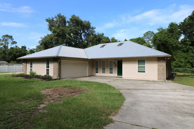 a front view of a house with a garden and trees